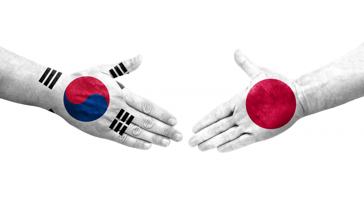 The national flags of South Korea (left) and Japan are embedded within images of shaking hands. (123rf)